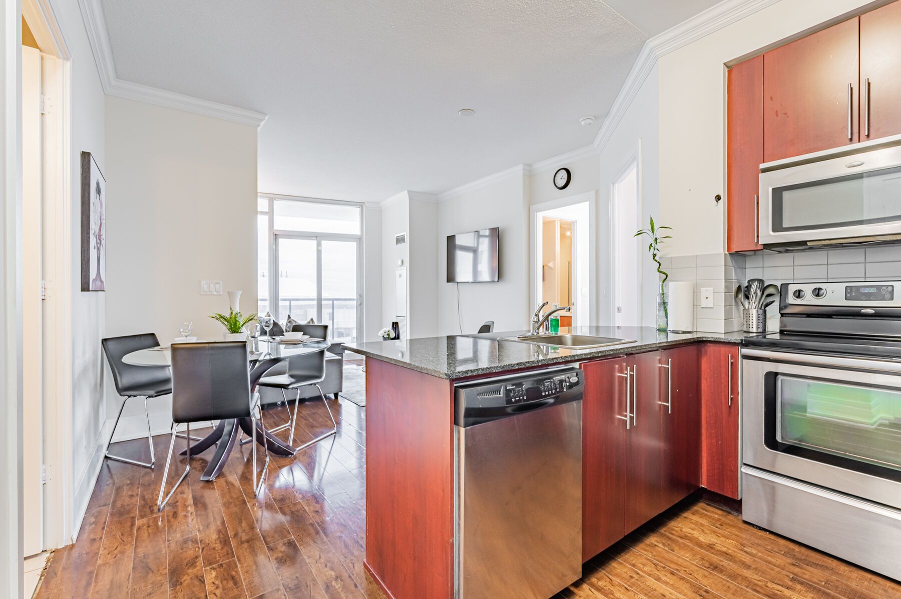 A modern kitchen with stainless steel appliances, a dishwasher, and wooden cabinets.