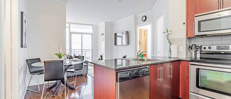 A modern kitchen with stainless steel appliances, a dishwasher, and wooden cabinets.