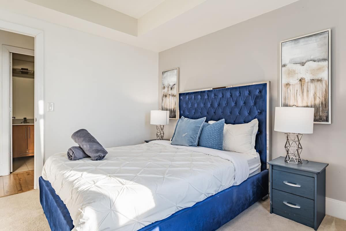 A bedroom with a bed, bedside tables, a wardrobe, and artwork on the walls.