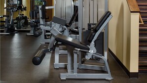 Een sportschool met diverse trainingsapparaten, waaronder een beendrukmachine en een buikspieroefening machine.