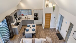 Een moderne keuken met een centraal eiland, geïntegreerde apparatuur en een eethoek met een tafel voor vier personen.