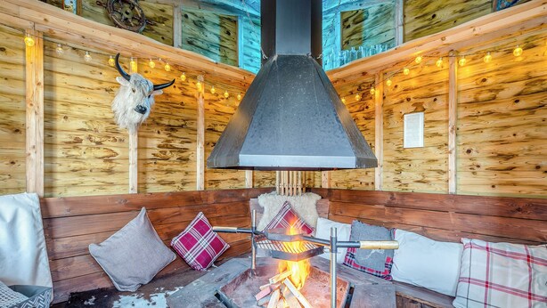 Een gezellig chaletinterieur met een houtkachel, houten wanden en decoratie van een koehoofd.