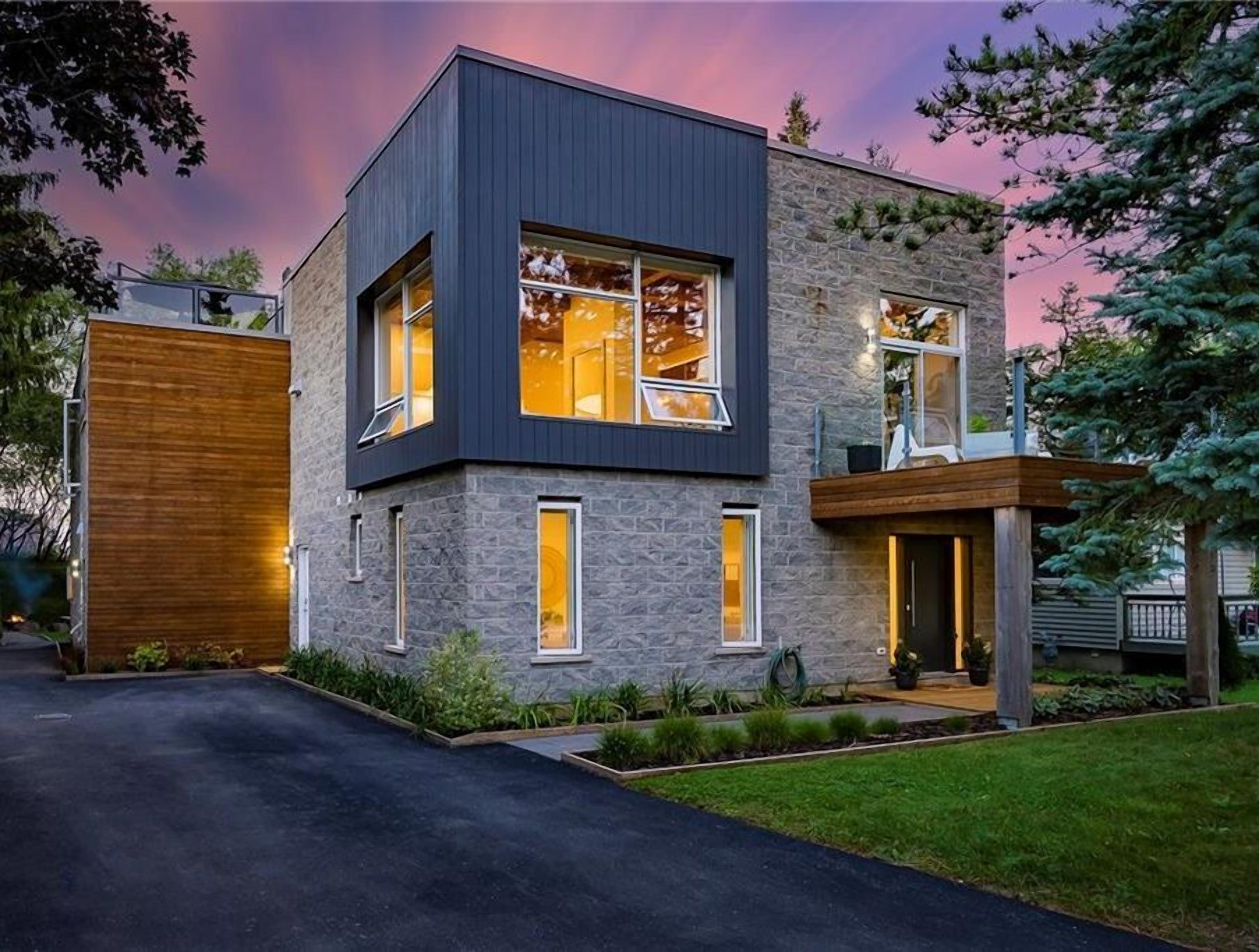 A modern two-story house with a garage, large windows, and a well-maintained lawn.