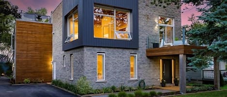 A modern two-story house with a garage, large windows, and a well-maintained lawn.