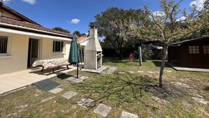 Una propietat residencial amb terrassa, una xemeneia, un arbre i una petita zona de jardí.