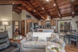 A spacious living room with a leather sofa, a dining area with a table and chairs, wooden cabinets, and a kitchen with modern appliances.