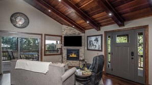 A living room with a fireplace, a television, and a door. - Moon Mountain Escape by Ruidoso Vacation Rentals (Ruidoso)