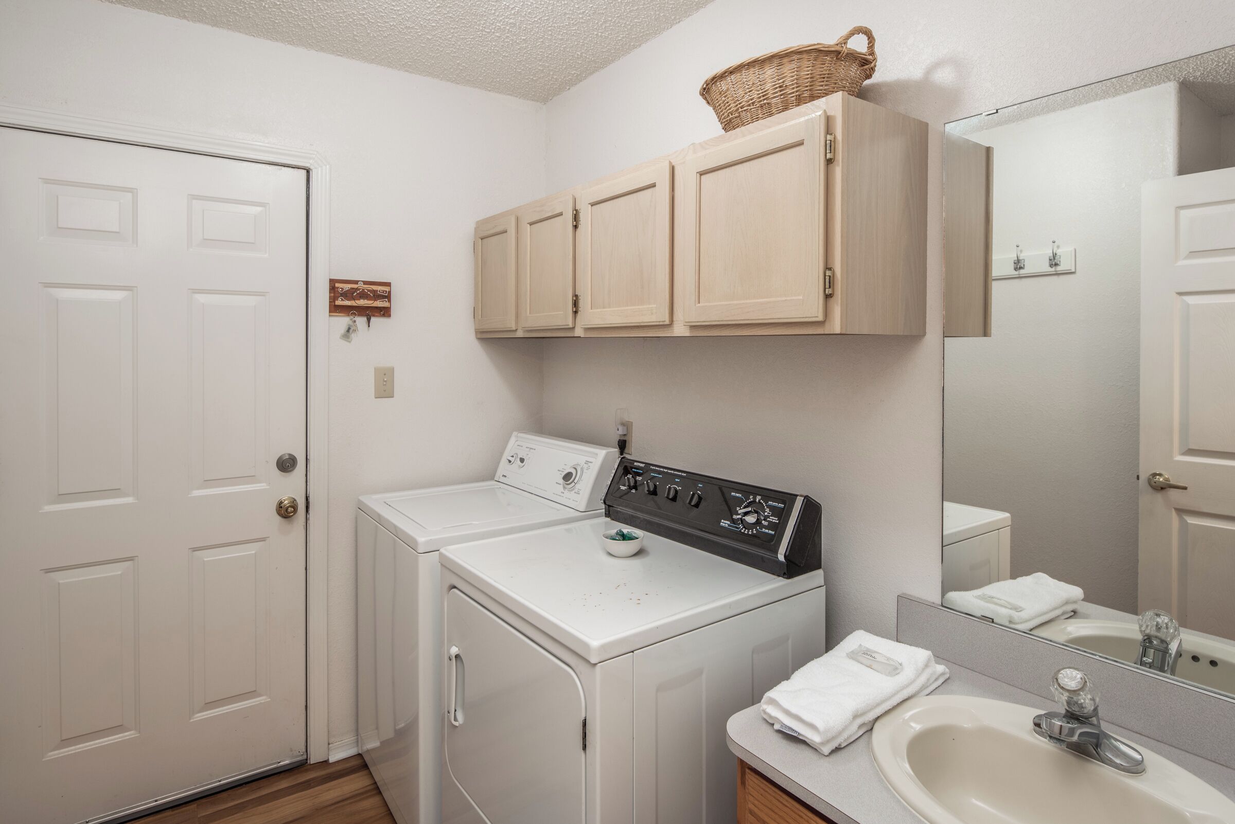 A laundry room with a washing machine, dryer, and a sink with a mirror above.