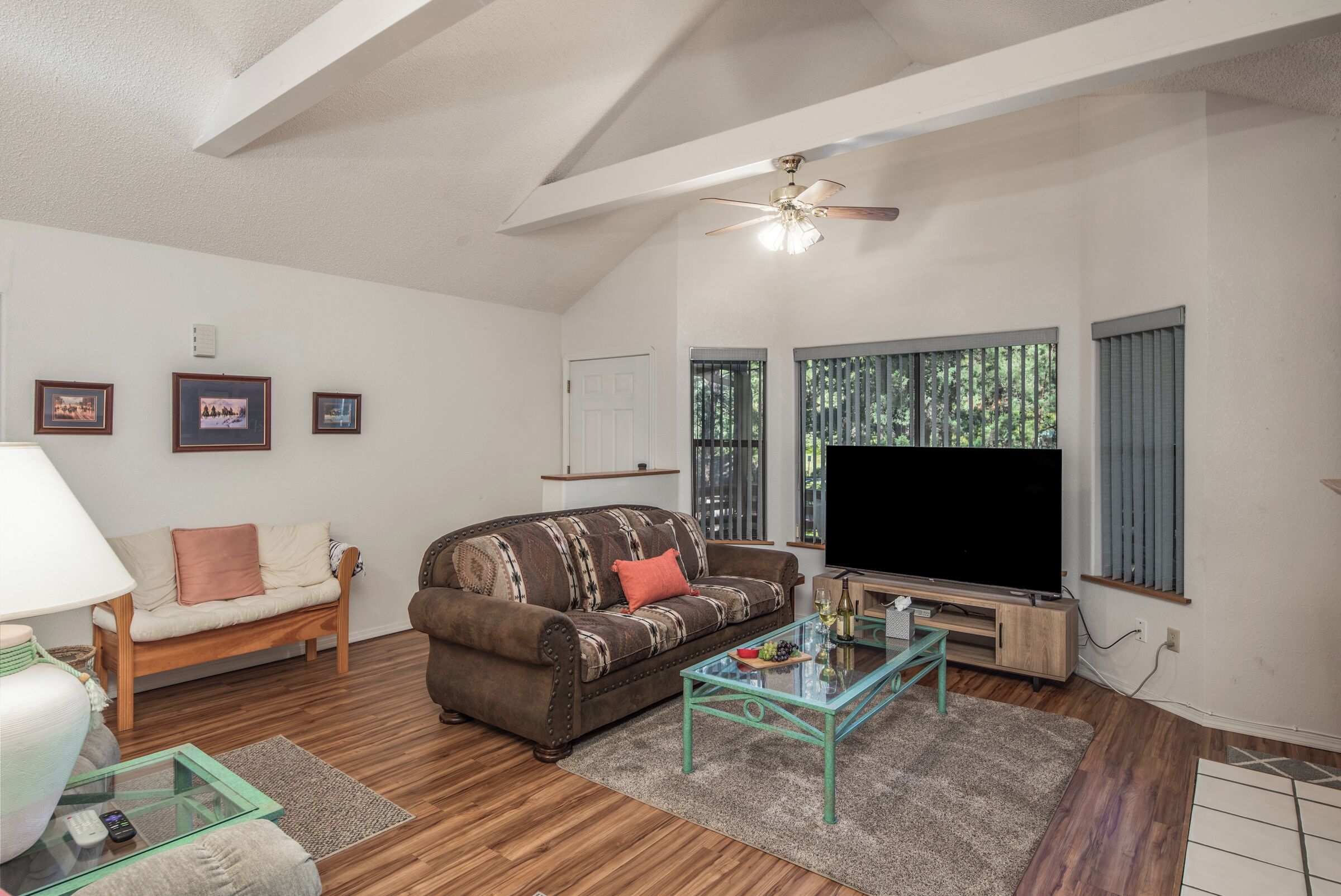 A living room with a sofa, a coffee table, a TV, and framed pictures on the wall.