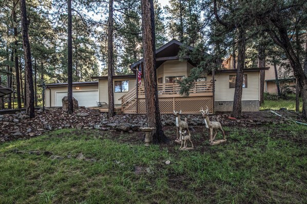 A cabin with a stone foundation, wooden deck, and a small porch. - Season 4 Art by Ruidoso Vacation Rentals (Ruidoso)