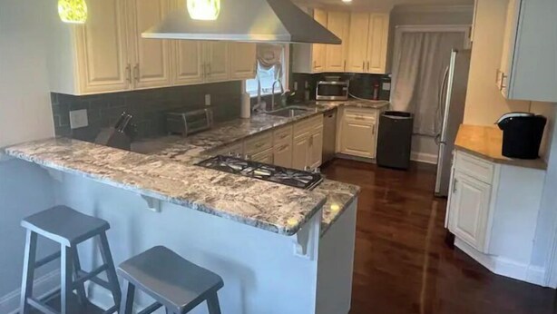 A kitchen with a central island, bar stools, a microwave, and a refrigerator. - Cheerful 4 bedroom home with all the updates (Newtown)