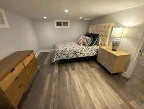 A bedroom with a bed, nightstand, dresser, and a window.