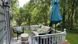 A wooden deck with a white railing, a sofa with cushions, a small round table, and a barbecue grill. - Cheerful 4 bedroom home with all the updates (Newtown)