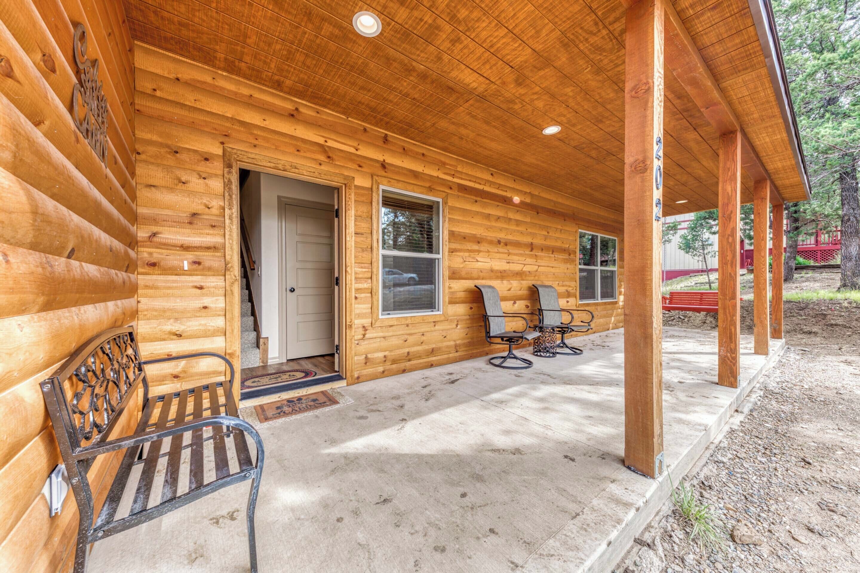 Une cabane en bois avec une véranda, deux chaises et un banc.