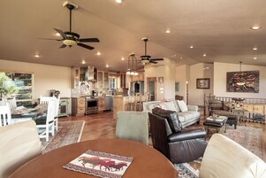 A spacious living area with a dining table, leather sofas, and a kitchen in the background.