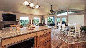 A spacious kitchen with granite countertops, a built-in oven, and a dining area with white chairs and a rug. - Alto Grand View by Ruidoso Vacation Rentals (Alto)