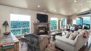 A spacious living room with a fireplace, large windows, and comfortable seating. - Alto Grand View by Ruidoso Vacation Rentals (Alto)