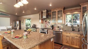 A spacious kitchen with granite countertops, wooden cabinets, and a central island. - Alto Grand View by Ruidoso Vacation Rentals (Alto)