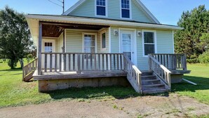 Ein zweistöckiges Haus mit Veranda, kleinem Vorgarten und einer hölzernen Treppe zum Eingang.