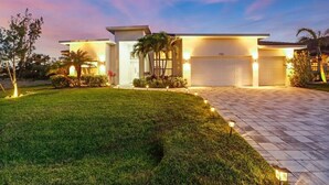 A modern two-story house with a well-maintained lawn, a driveway, and a garage. - Villa Aviator (Cape Coral)