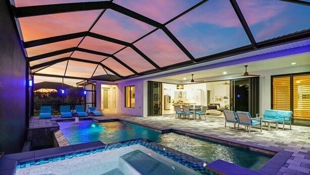 A modern indoor pool area with a glass ceiling, lounge chairs, and a hot tub. - Villa Aviator (Cape Coral)