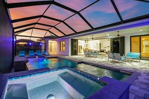 Een moderne binnenzwembadruimte met glazen dak, lounge fauteuils en een whirlpool.