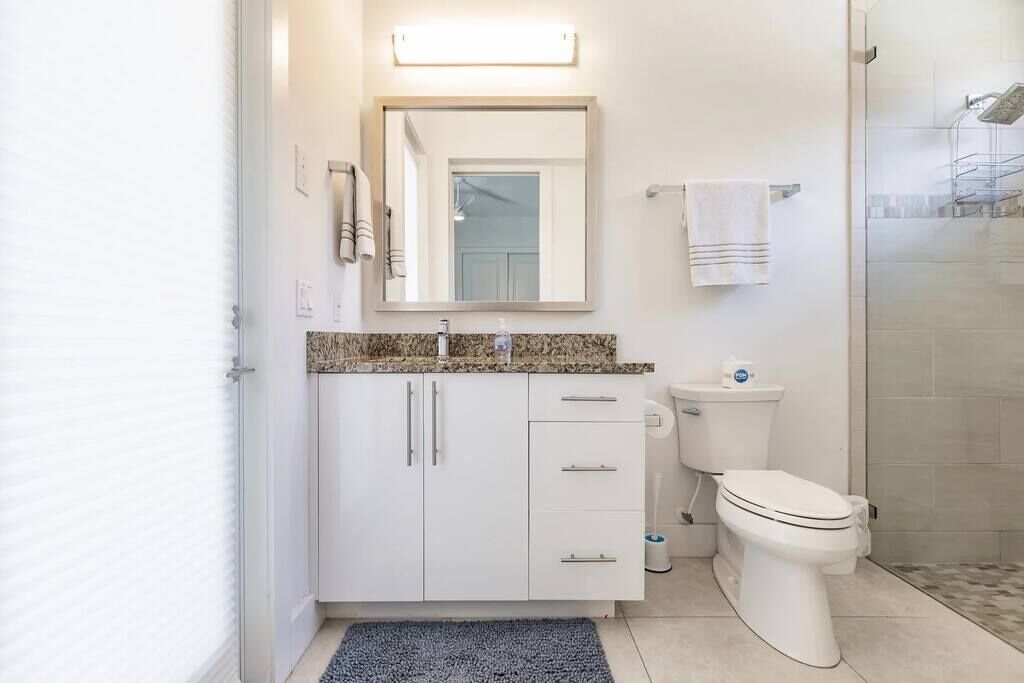 A modern bathroom with a white vanity, a toilet, and a shower area.