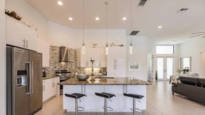 A modern kitchen with a central island, stainless steel appliances, and pendant lighting. - Villa Aviator (Cape Coral)