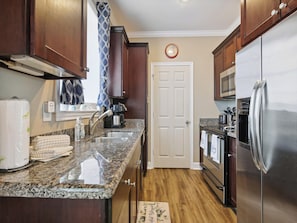 A modern kitchen with granite countertops, stainless steel appliances, and wooden cabinets. - Dawn 223 - Buena Vista by Ryson Vacation Rentals (Galveston)