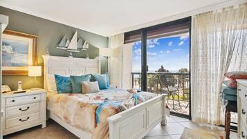 Un dormitorio con cama, mesita de noche y cómoda. Cuenta con un balcón con vistas al mar.