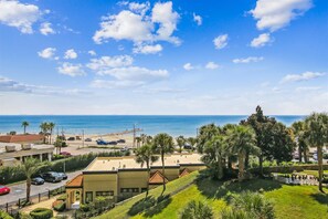 Hotel à beira-mar com vista para o mar, área de estacionamento e um jardim paisagístico.