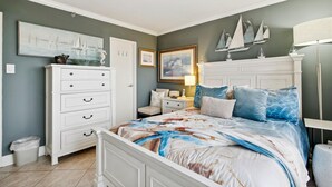 Une chambre à coucher comprenant un lit, une commode, une table de chevet et des œuvres d’art murales.