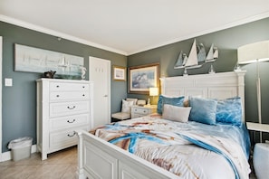 Een slaapkamer met een bed, een dressoir, nachtkastje en wanddecoratie.