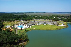 Vista aérea de um resort com uma piscina grande, um campo de golfe e um lago.