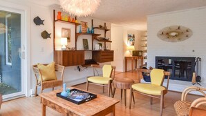A living room with a fireplace, wooden furniture, and wall decorations. - Short Walk to Long Pond Swimming Beach! (Wellfleet)