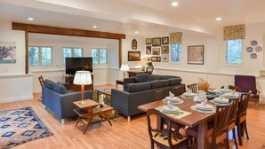 A living room with a TV, sofas, a dining table set, and a fireplace. - Short Walk to Long Pond Swimming Beach! (Wellfleet)