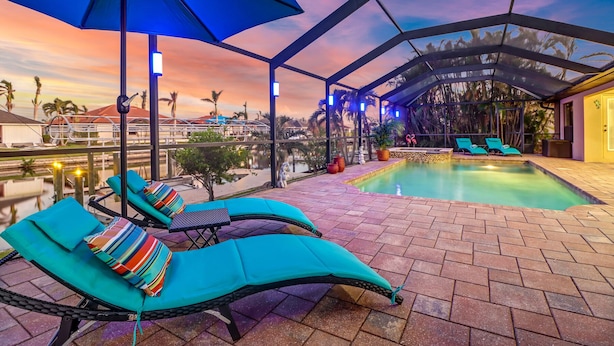 Un espace piscine sur le toit, avec des chaises longues et des parasols, une vue sur le paysage urbain et une piscine agrémentée d’une petite cascade.