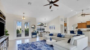Un salon spacieux avec un canapé blanc, un tapis à motifs bleus et un coin repas comprenant une table et des chaises.