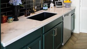 A modern kitchen with black tiled backsplash, gold fixtures, and a marble countertop. - Mr. Nomad: Parisian PopHouse in Uptown (Dallas)