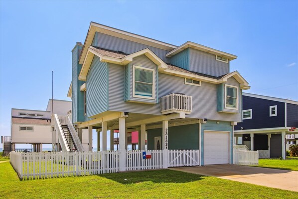 A two-story residential building with a covered porch and a white picket fence.