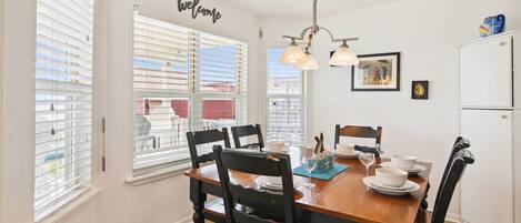 Un comedor con mesa de madera, sillas negras y refrigerador blanco.