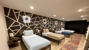 A hotel room with three beds, a patterned wall, and a colorful rug. - Nice and modern decor, 4BR 3BA, remodeled (Hagerstown)