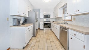 A modern kitchen with white cabinetry, a stainless steel refrigerator, a microwave, an oven, and a dishwasher. - Nice and modern decor, 4BR 3BA, remodeled (Hagerstown)