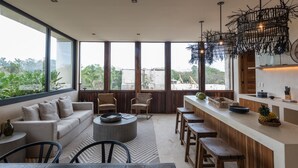 A modern kitchen with a bar area, large windows, and a view of the outdoors. - Unho Tulum (Tulum)