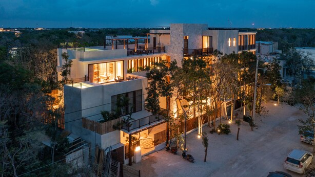 A modern multi-story house with a spacious outdoor area, large windows, and a view of the surrounding landscape. - Unho Tulum (Tulum)