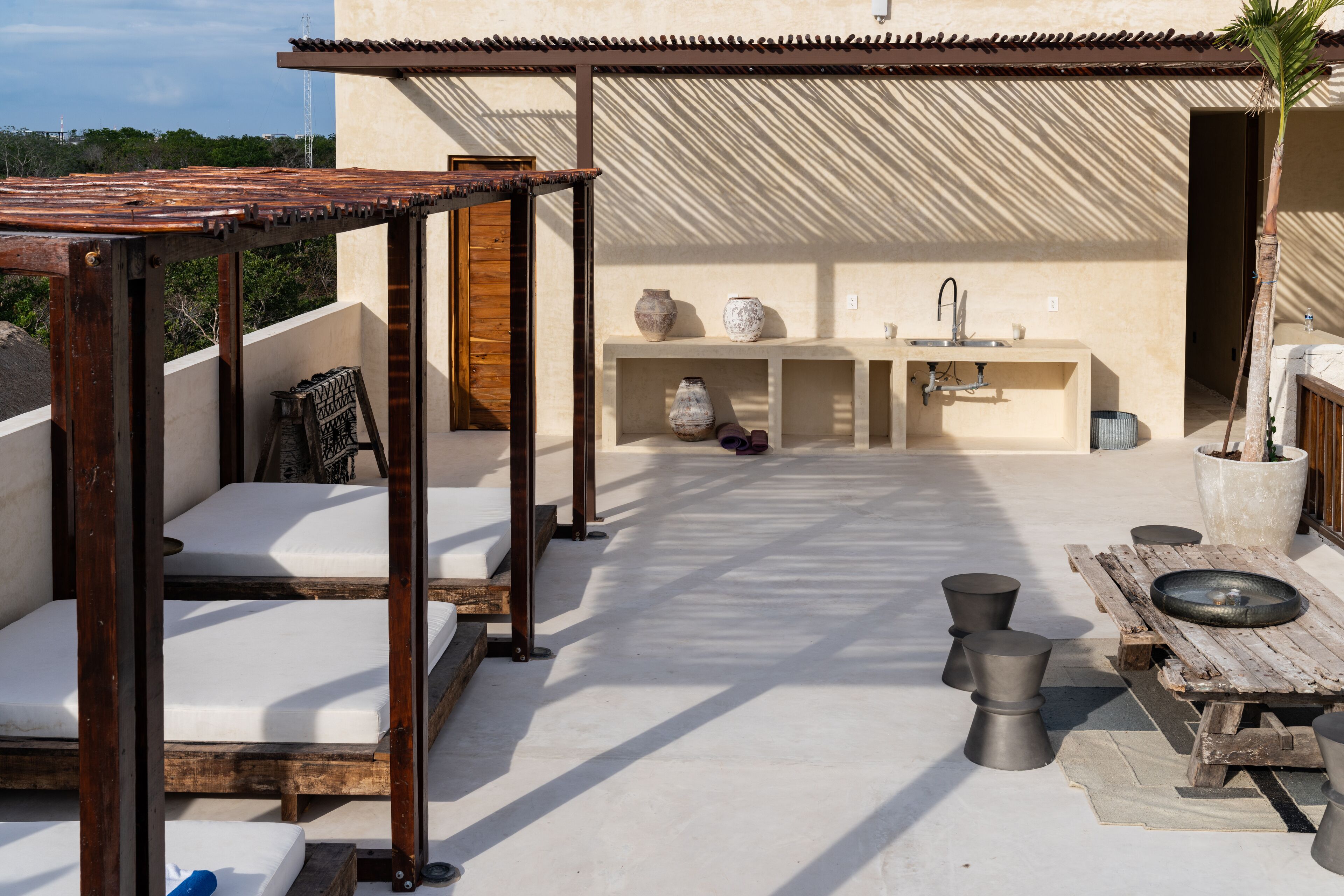 A rooftop patio with wooden furniture, a sink, and decorative vases.