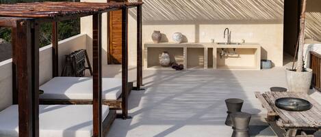 A rooftop patio with wooden furniture, a sink, and decorative vases.