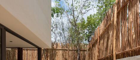 Un patio moderno al aire libre con cerramiento de madera, un área de estar con sillas y una pequeña fuente de agua.
