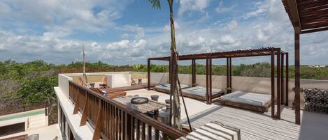 A rooftop terrace with a wooden pergola, lounge chairs, and a small pool.