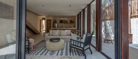 A modern living room with a sofa, a coffee table, and a wooden bench. A staircase leads to an upper level.
